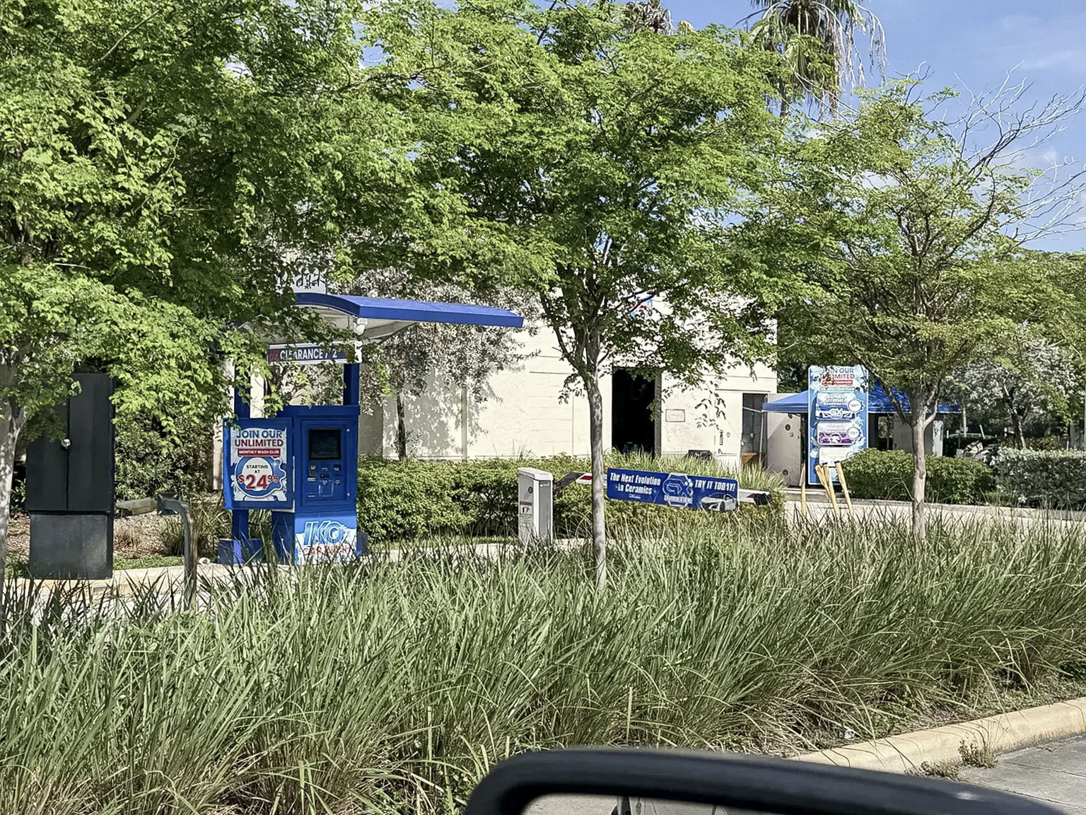 Car wash pay station and landscaped vehicle approach at a fuel site